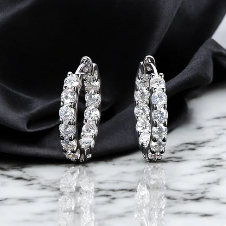 Pair of diamond hoop earrings on a black fabric and marble surface